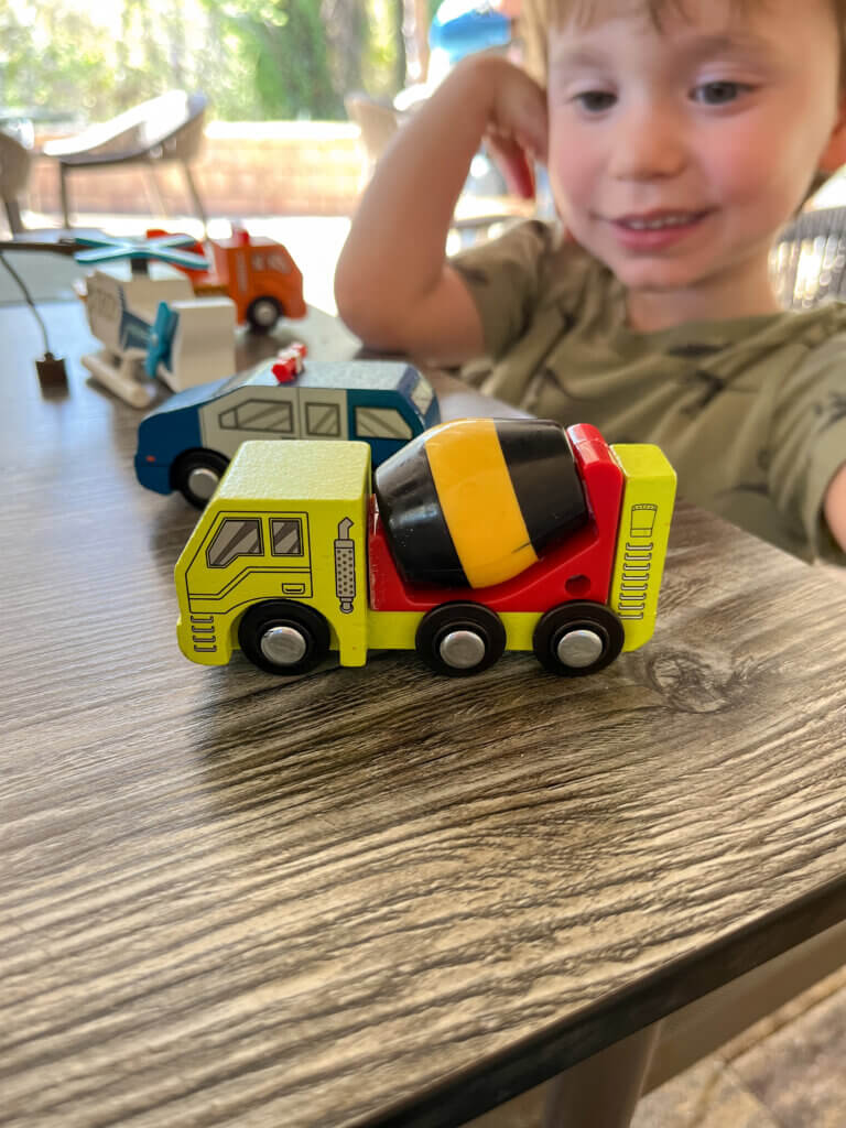 A boy plays with small wooden cement mixer - a toy on our restaurant essentials list.